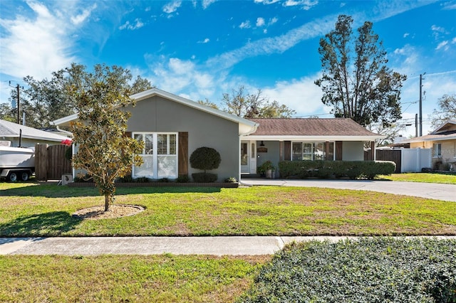 ranch-style house featuring stucco siding, covered porch, fence, driveway, and a front lawn