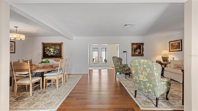 dining room with wood finished floors, visible vents, french doors, beamed ceiling, and an inviting chandelier