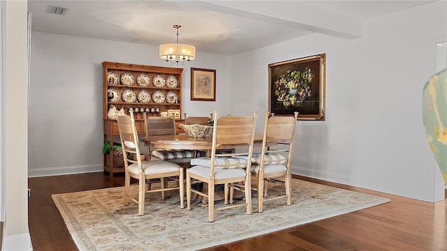 dining space featuring baseboards, visible vents, dark wood finished floors, and a notable chandelier