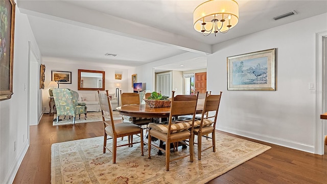 dining room with baseboards, wood finished floors, visible vents, and an inviting chandelier