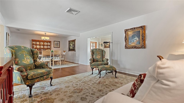 living area featuring baseboards, visible vents, and wood finished floors