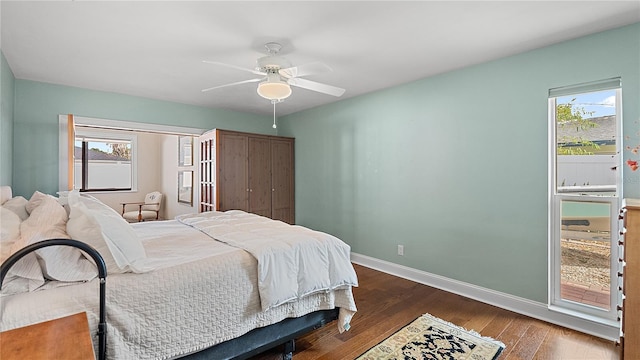 bedroom featuring ceiling fan, multiple windows, wood finished floors, and baseboards