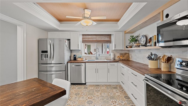 kitchen featuring a sink, white cabinets, wooden counters, appliances with stainless steel finishes, and a raised ceiling