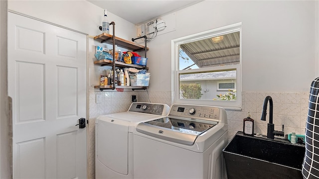 laundry room with laundry area, washer and clothes dryer, a wainscoted wall, a sink, and tile walls