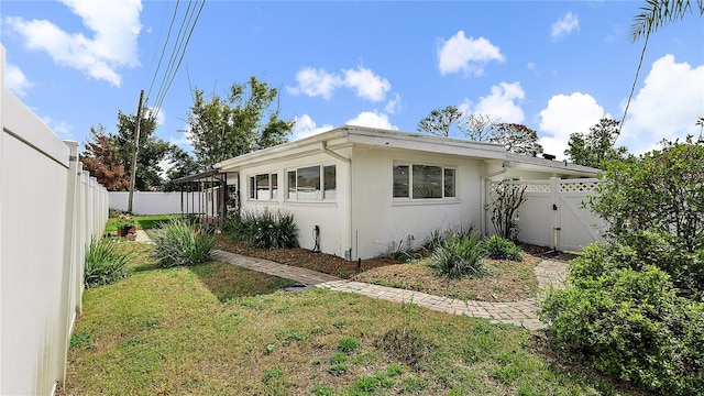 view of home's exterior with a fenced backyard, a lawn, and stucco siding