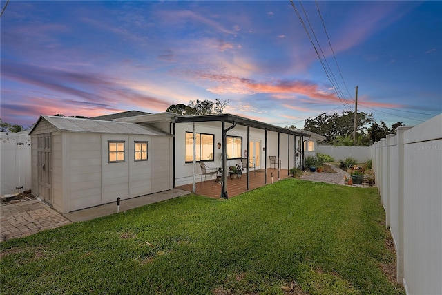 back of house at dusk with a fenced backyard, a lawn, and a patio