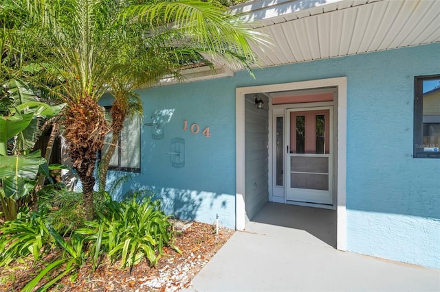 doorway to property featuring stucco siding