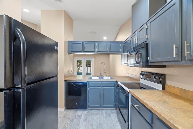 kitchen with black appliances, blue cabinetry, light countertops, and a sink