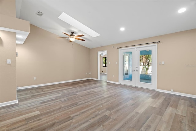 interior space featuring vaulted ceiling with skylight, visible vents, light wood-type flooring, and baseboards