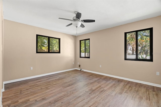 empty room with ceiling fan, baseboards, and wood finished floors