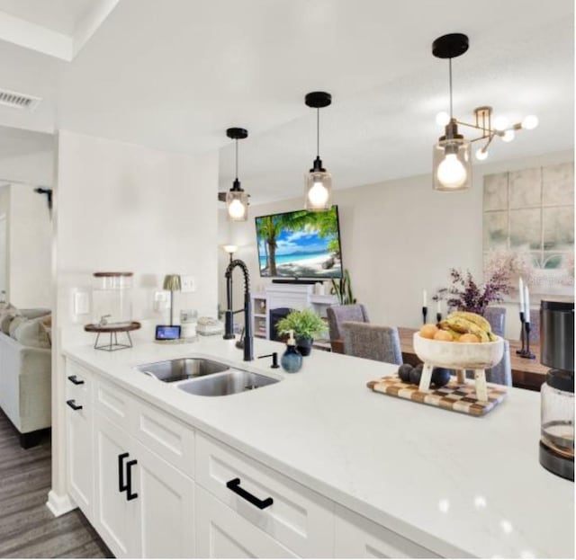 kitchen with sink, white cabinetry, hanging light fixtures, and dark wood-type flooring