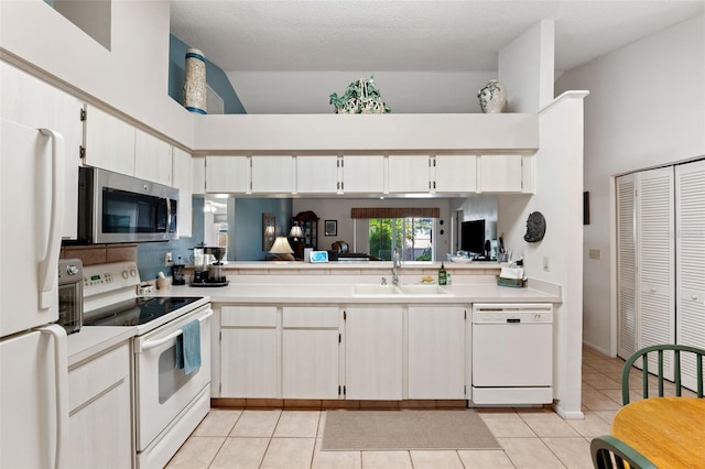 kitchen with white appliances, light tile patterned floors, light countertops, and a sink