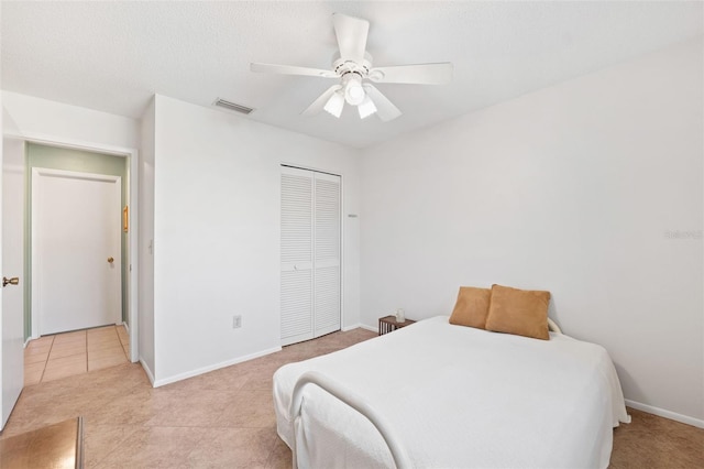 bedroom with baseboards, visible vents, a ceiling fan, a closet, and light tile patterned flooring