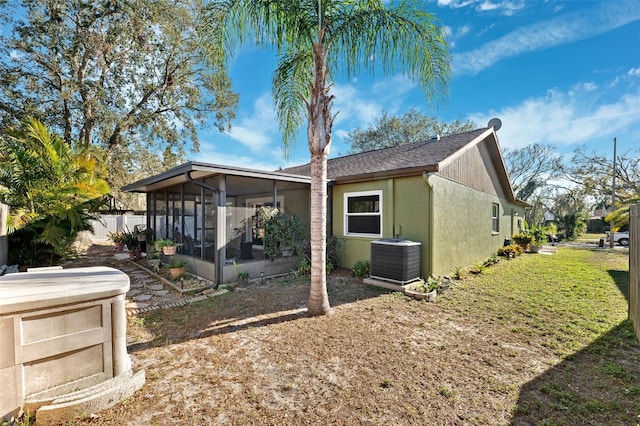 view of home's exterior featuring stucco siding, central air condition unit, a lawn, a sunroom, and fence