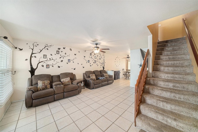 living area with a ceiling fan, light tile patterned floors, a textured ceiling, and stairs