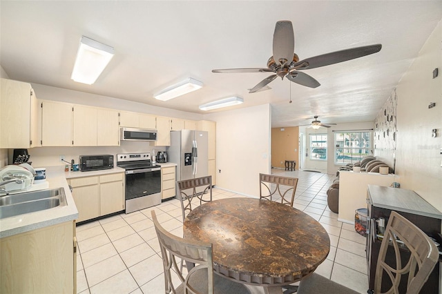 kitchen featuring cream cabinetry, light tile patterned floors, light countertops, appliances with stainless steel finishes, and a sink