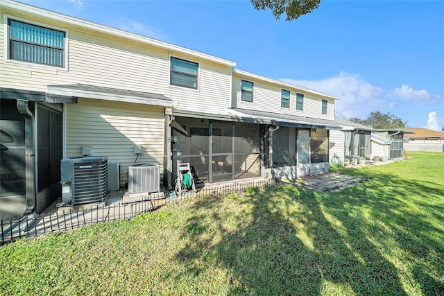 rear view of house with central AC unit, a lawn, and a sunroom