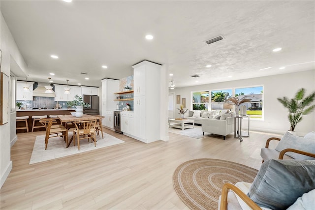 living area featuring beverage cooler, visible vents, recessed lighting, and light wood-type flooring