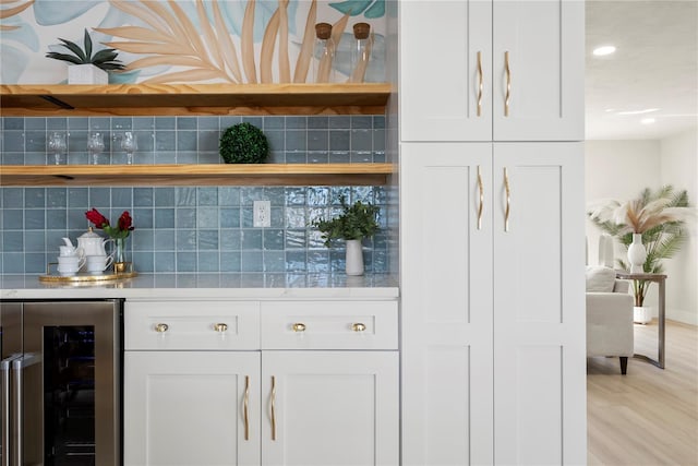 bar with backsplash, beverage cooler, recessed lighting, light wood-style flooring, and a bar