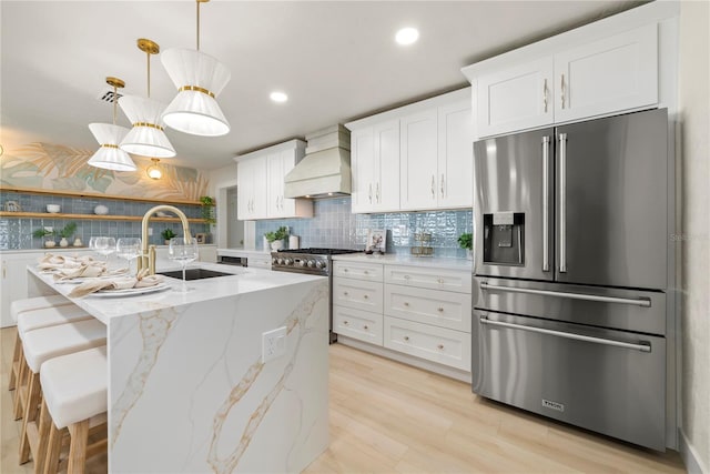 kitchen featuring custom range hood, decorative backsplash, stainless steel appliances, white cabinetry, and a sink