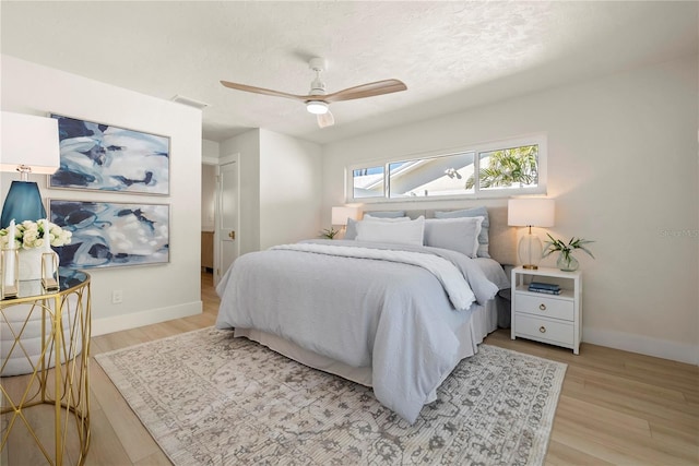 bedroom with light wood-style flooring, baseboards, visible vents, and a textured ceiling