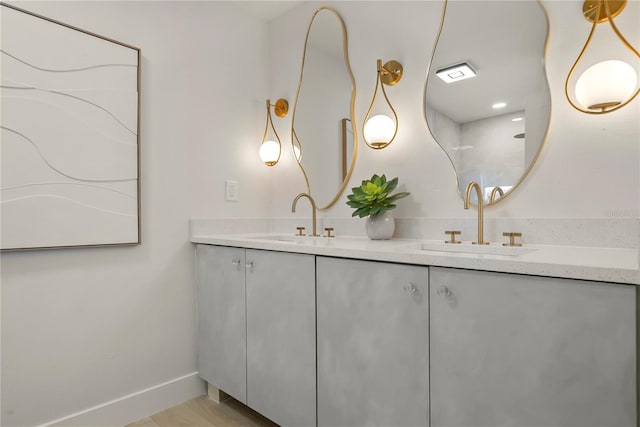 full bathroom featuring a sink, baseboards, wood finished floors, and double vanity