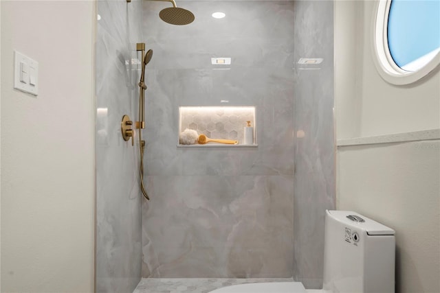 bathroom featuring a marble finish shower and toilet