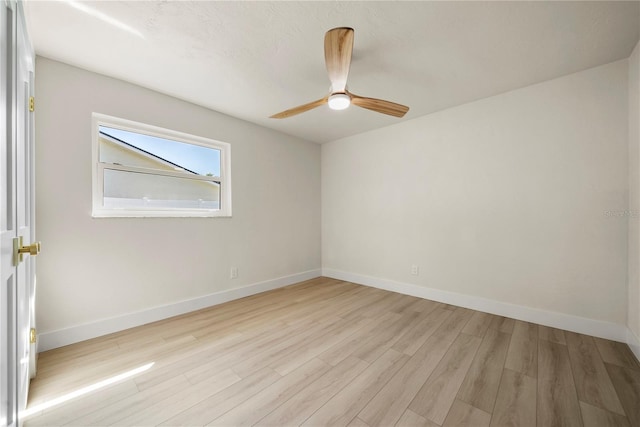 empty room with a ceiling fan, light wood-style floors, and baseboards