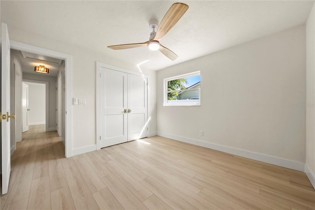 unfurnished bedroom with light wood finished floors, a closet, a ceiling fan, and baseboards