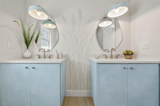 bathroom with wood finished floors, two vanities, and a sink