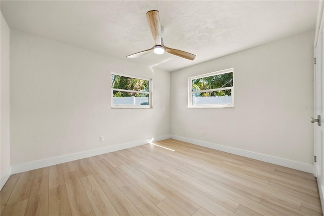 spare room featuring baseboards, light wood-style floors, and ceiling fan