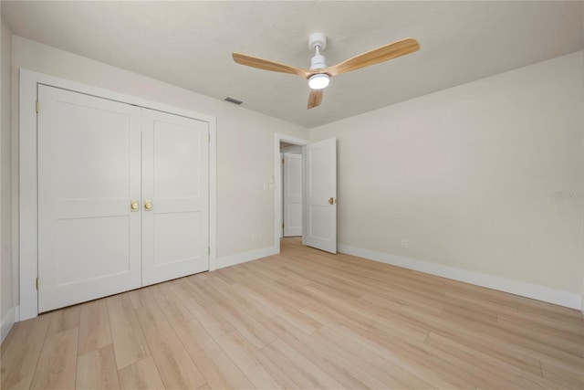 unfurnished bedroom with visible vents, wood finished floors, a closet, baseboards, and ceiling fan