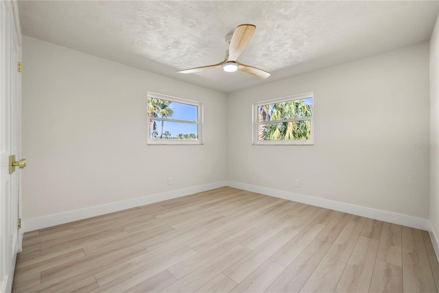 spare room featuring a textured ceiling, baseboards, light wood-type flooring, and ceiling fan