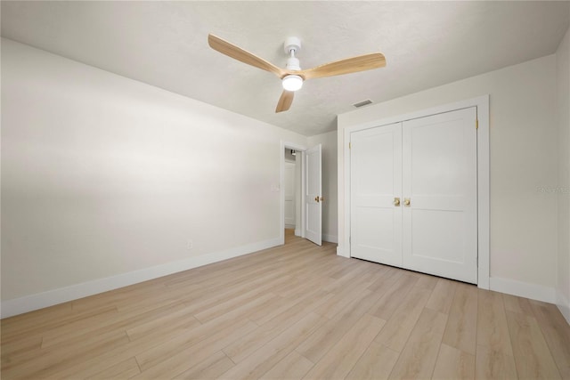 unfurnished bedroom with wood finished floors, visible vents, baseboards, ceiling fan, and a closet