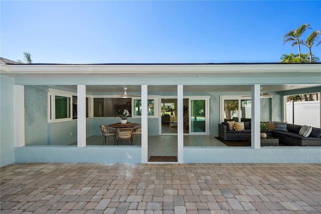 back of property with stucco siding, a patio, outdoor lounge area, and a sunroom