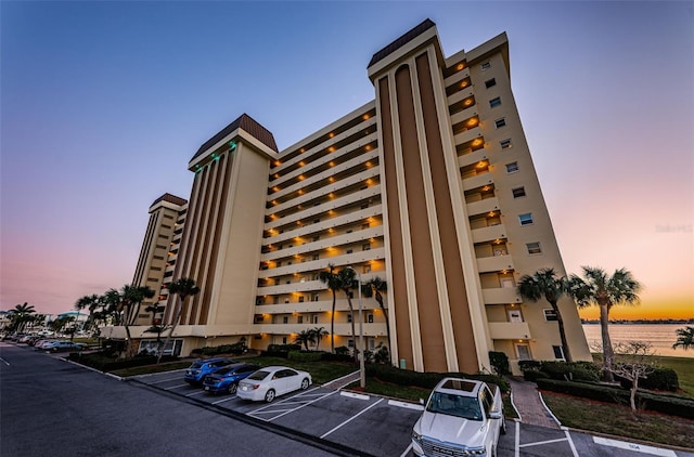 property at dusk with a water view and uncovered parking