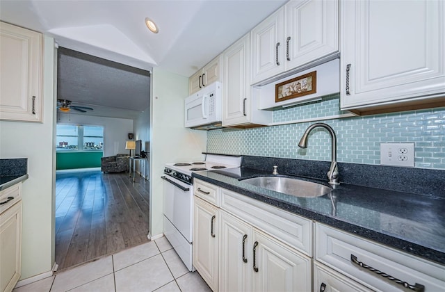 kitchen with white appliances, white cabinets, a sink, and dark stone countertops