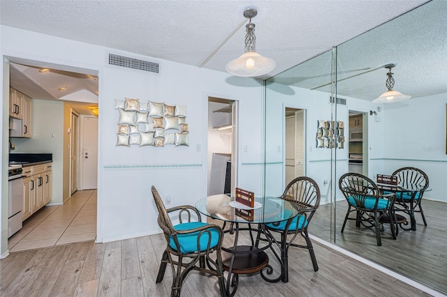 dining room with a textured ceiling, visible vents, and light wood-style floors