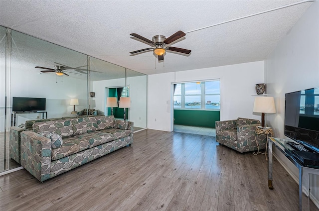 living area featuring a ceiling fan, a textured ceiling, and light wood finished floors