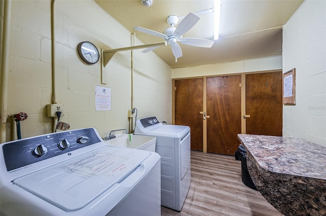 laundry area with laundry area, a sink, independent washer and dryer, light wood-type flooring, and concrete block wall