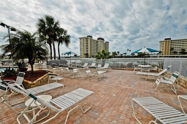 view of patio / terrace with a water view, a view of city, and fence