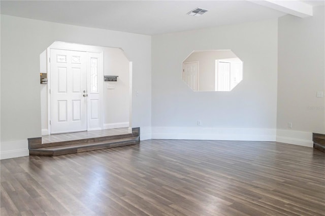 interior space featuring arched walkways, wood finished floors, visible vents, and baseboards