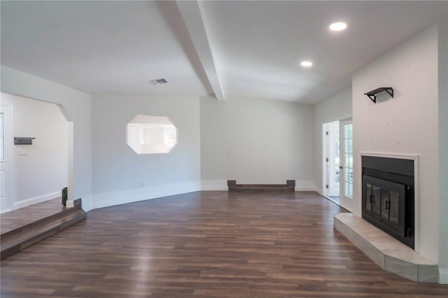 unfurnished living room featuring a glass covered fireplace, beamed ceiling, wood finished floors, and visible vents