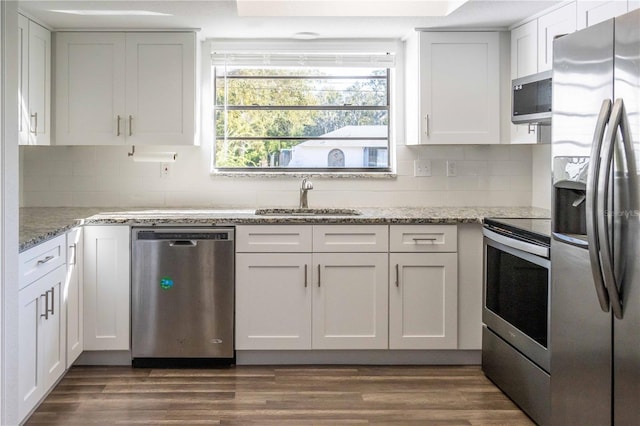 kitchen featuring stainless steel appliances, tasteful backsplash, dark wood-type flooring, white cabinetry, and a sink