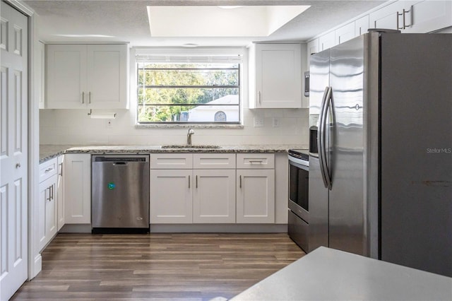 kitchen featuring dark wood-style floors, decorative backsplash, stainless steel appliances, and a sink