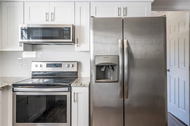 kitchen with stainless steel appliances, white cabinets, decorative backsplash, and light stone countertops