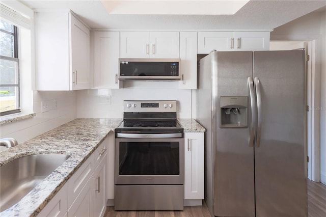 kitchen with a wealth of natural light, white cabinetry, appliances with stainless steel finishes, and a sink