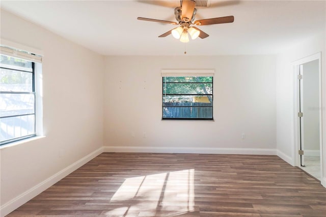 empty room with wood finished floors, a wealth of natural light, and baseboards