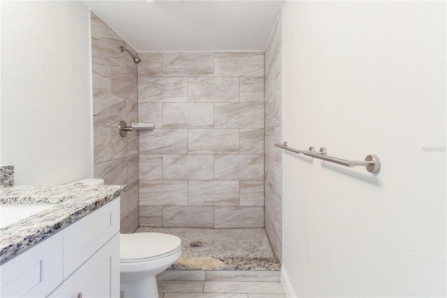 full bathroom featuring toilet, tiled shower, and vanity