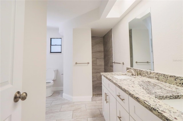 bathroom with baseboards, a sink, toilet, and double vanity